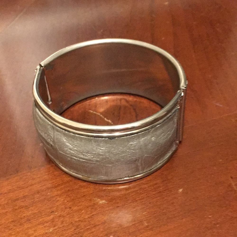 Hinged bracelet with gray leather-like look.